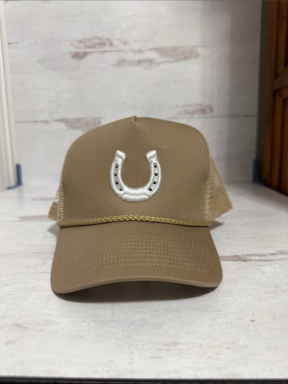 Tan Horseshoe Trucker Cap - all seated in a barn